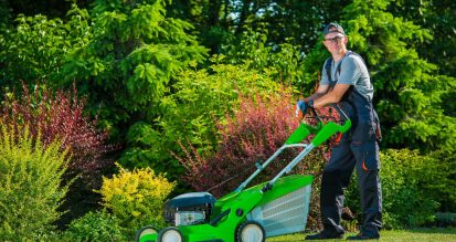 Smiling Professional Gardener with His Gasoline Lawn Mower. Professional Summer Landscaping Works
